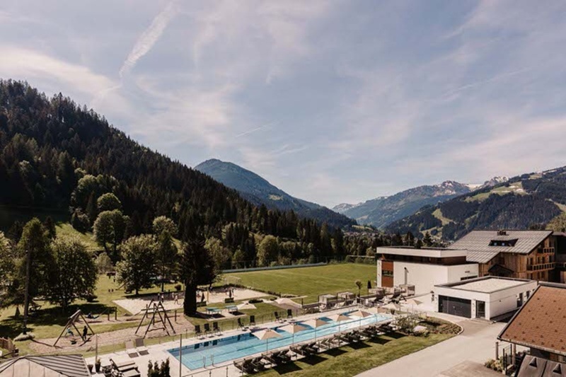 Hofgut-Wagrain-Apartment-Lifestyle-Resort-Wagrain-gartenanlage 402-2 Sommerliche Garten- und Poollandschaft im Hofgut Wagrain – 25-Meter-Sportbecken, Relax-Lounges und Sportwiese vor traumhafter Alpenkulisse im Salzburger Land.