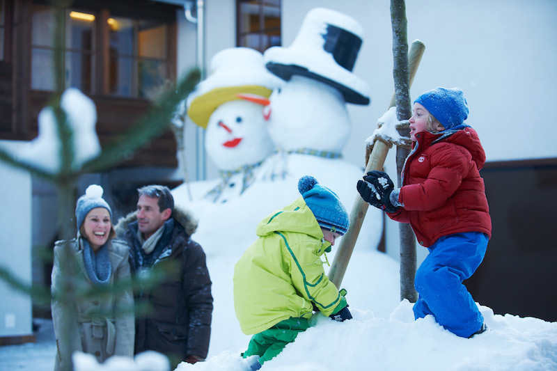 Die Kids bauen auf dem autofreien Platz Schneemänner während die Eltern bummeln und shoppenSüdtirol mit Kindern im Winter